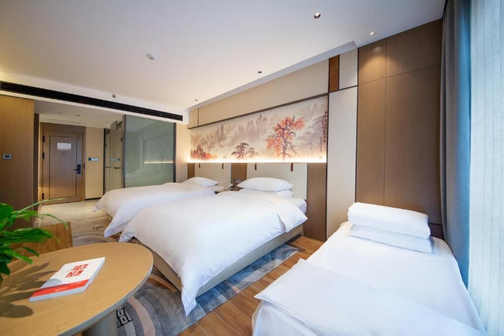 Een hotelkamer met twee bedden, een ronde tafel en een groot schilderij aan de muur.