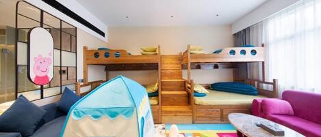 A children's room with bunk beds, a play tent, a colorful play mat, a sofa, and a table.