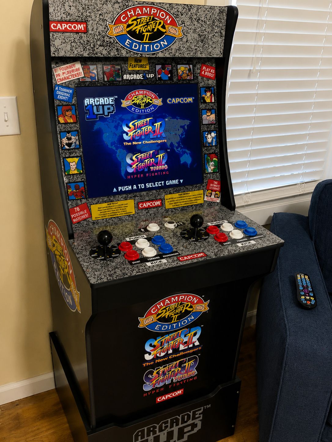 Una máquina arcade CAPCOM con una etiqueta que dice 'Champion Street Fighter II Edition', mostrando una selección de juegos y un joystick.