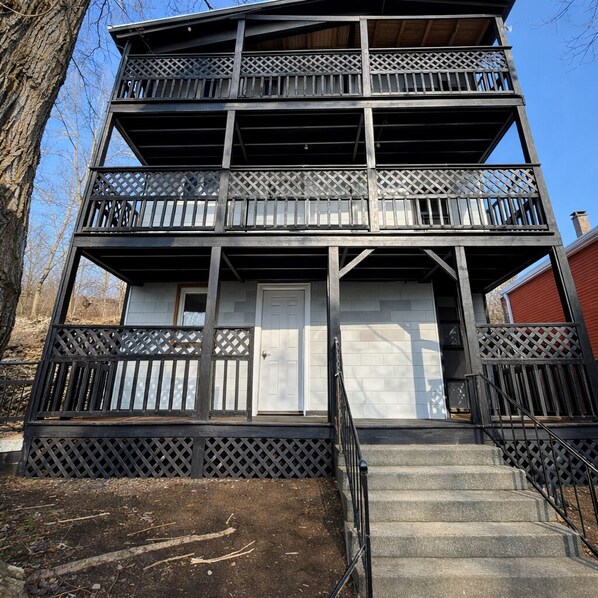 A multi-story building with balconies, a door, and a staircase leading to the entrance.