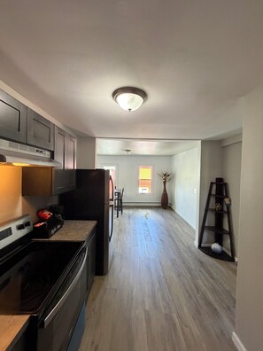 A kitchen with a stove, cabinets, and a dining area with chairs.