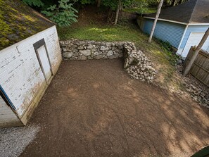 A dirt patio area with a stone wall and a wooden fence. - Modern 2BR Getaway with Arcade Game Room &  Lounge Near Mohegan Sun & Foxwoods (Norwich)