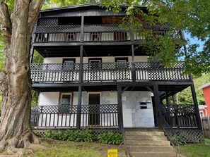 Un immeuble à plusieurs étages, doté de balcons, d’un escalier et d’un arbre au premier plan.
