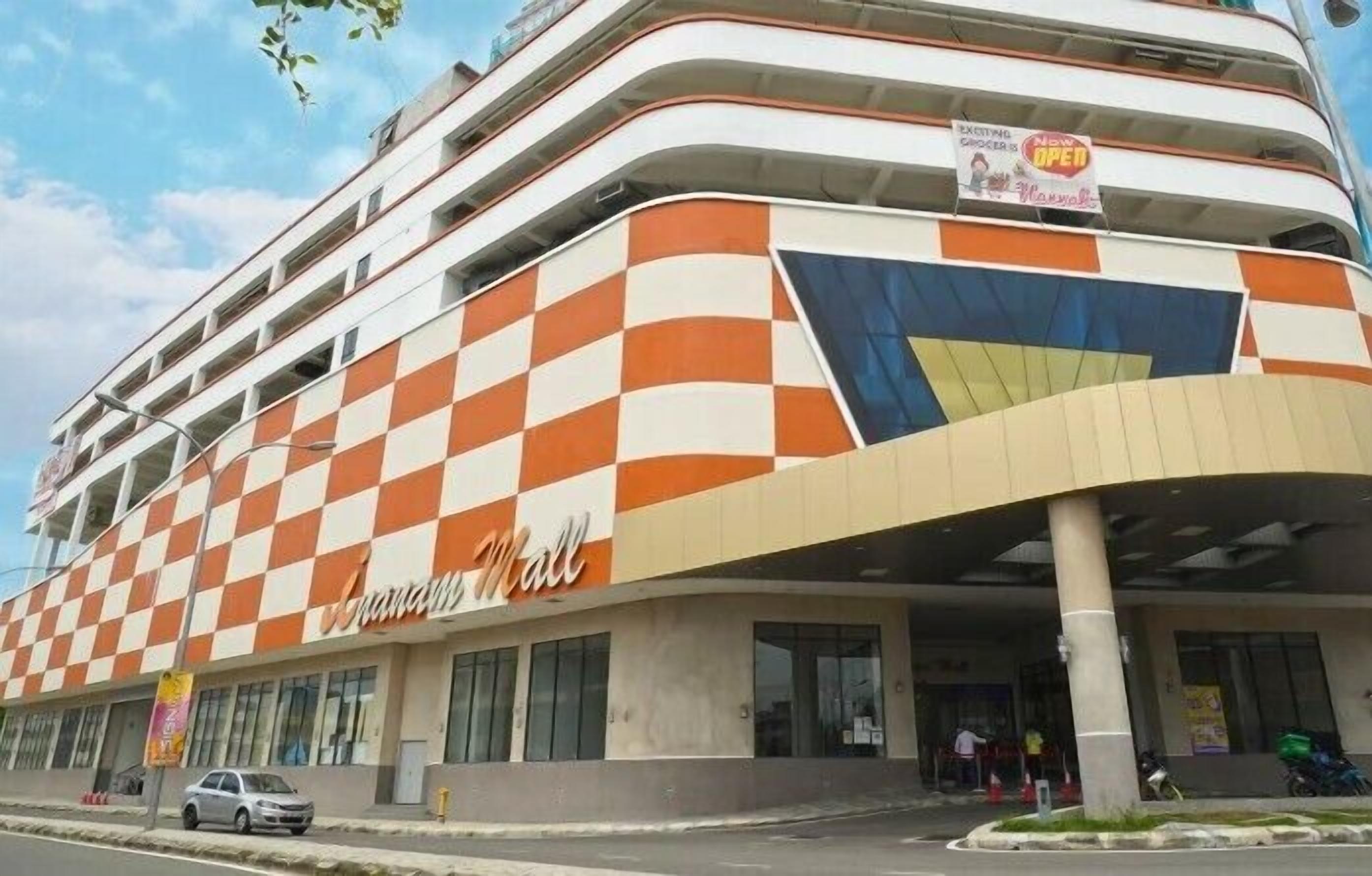 Un edificio de varios pisos con fachada a cuadros y un cartel que anuncia la apertura de un nuevo supermercado.