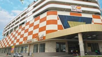 A multi-story building with a checkered facade and a sign indicating a new grocery store opening.