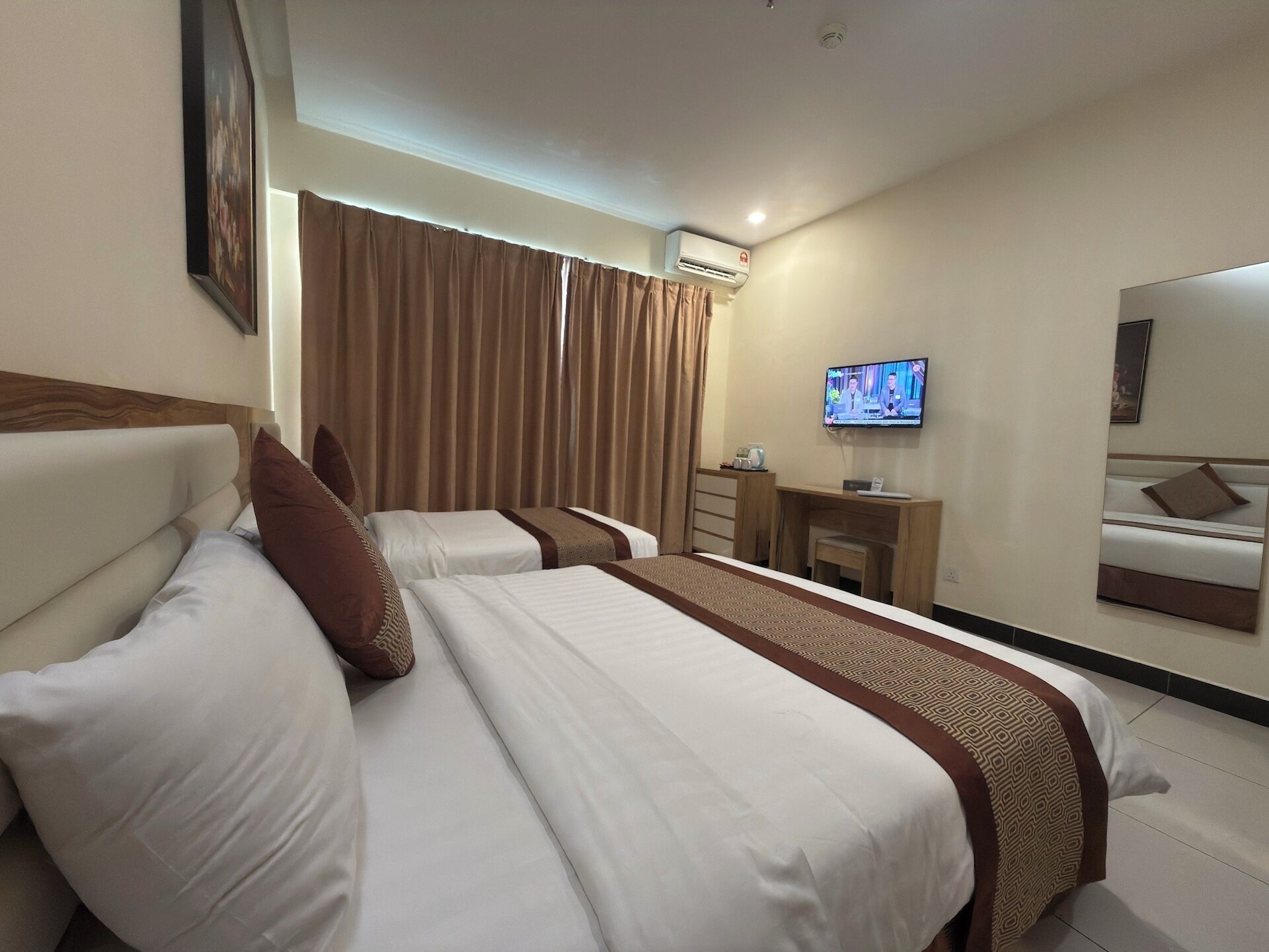 Habitación de hotel con dos camas, un escritorio, un televisor y un equipo de aire acondicionado.