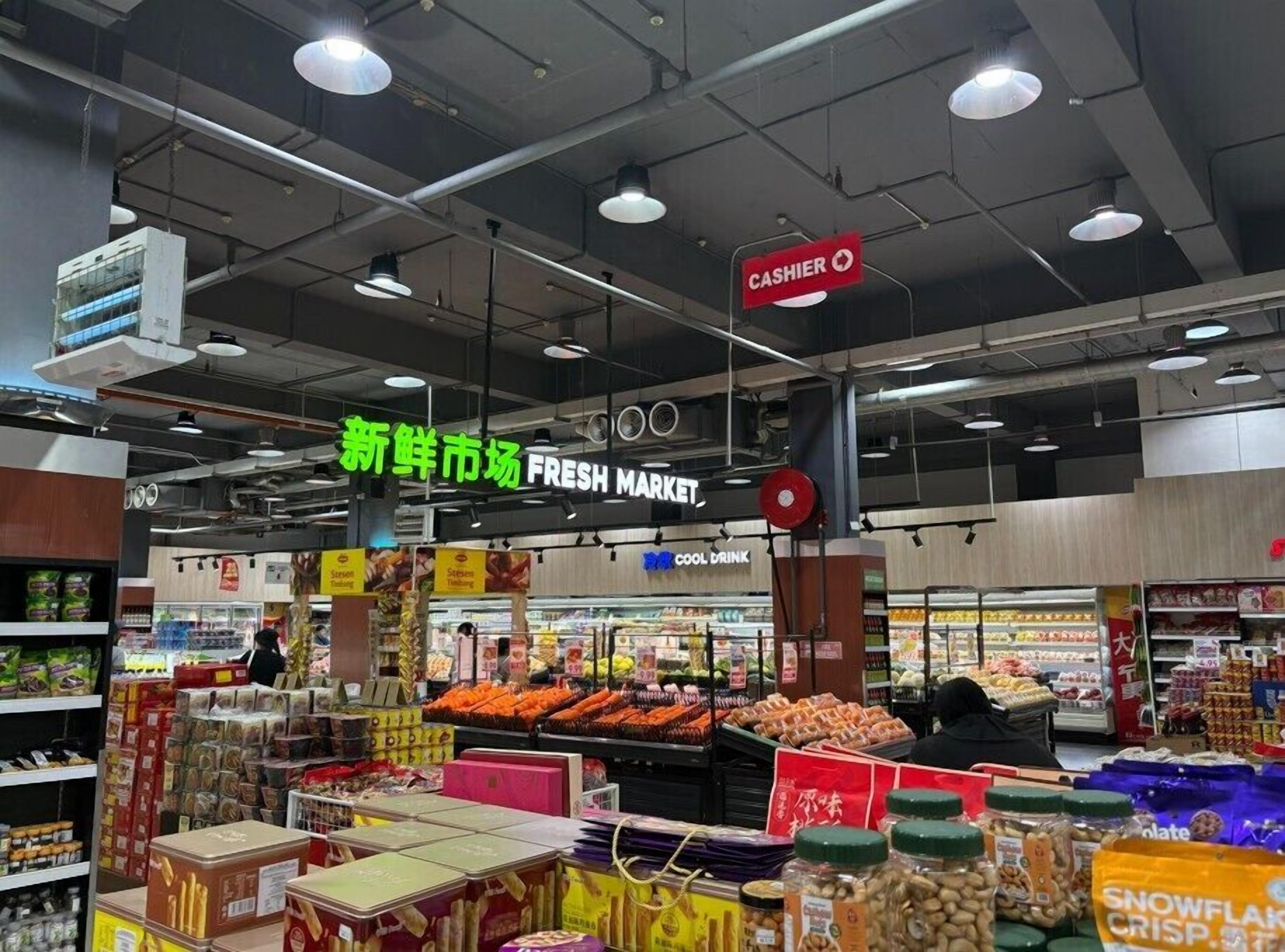 A supermarket interior with a fresh market section, a cashier, and various food products on display.