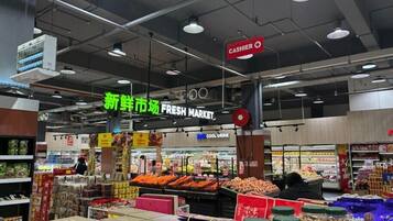 A supermarket interior with a fresh market section, a cashier, and various food products on display.