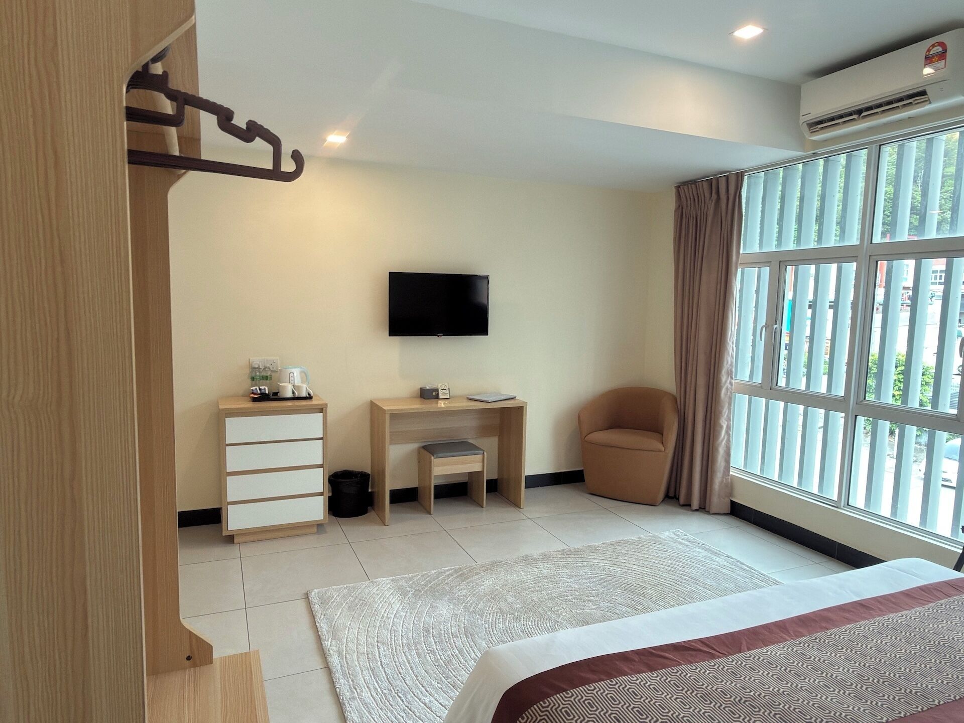 Ein Hotelzimmer mit Bett, Schreibtisch, Stuhl, Fernseher und einem großen Fenster.