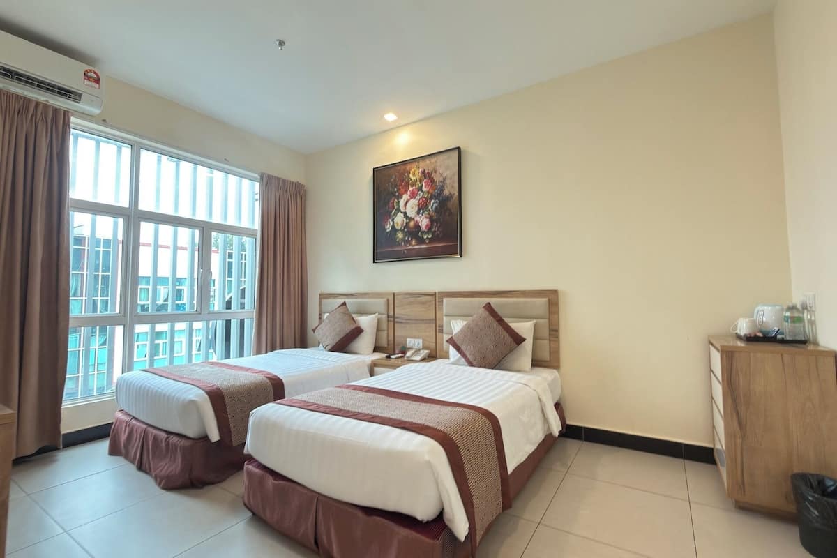 Habitación de hotel con dos camas, una ventana con cortinas, un cuadro en la pared y un armario pequeño.