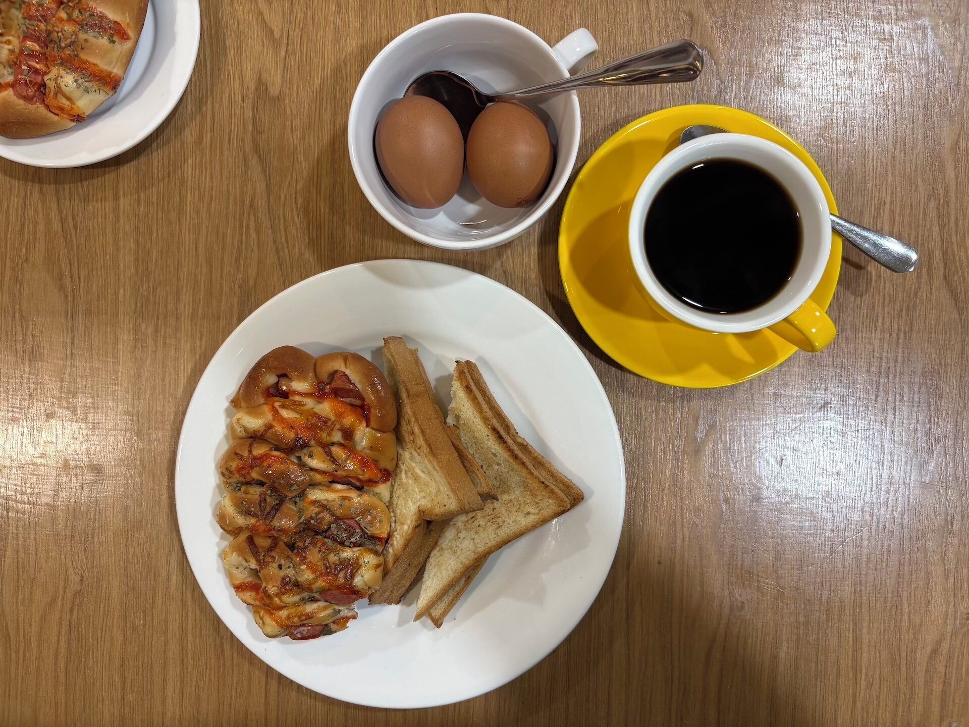 En morgenmadstallerken med ristet brød og røræg, en kop kaffe og en tallerken med pizza.