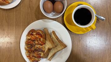 En morgenmadstallerken med ristet brød og røræg, en kop kaffe og en tallerken med pizza.