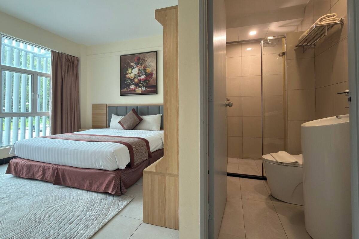 Una habitación de hotel con cama, ducha y baño.