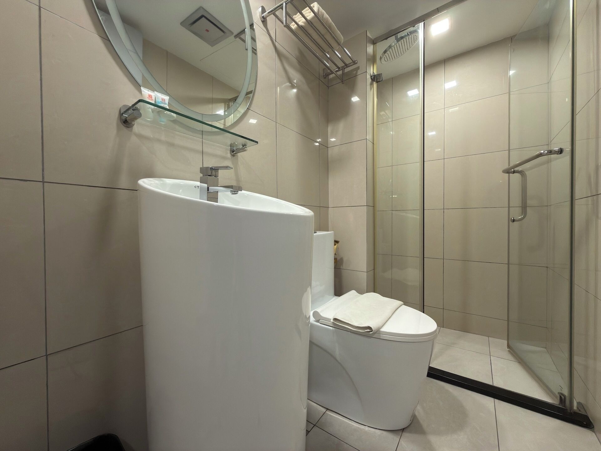 A modern bathroom with a large white sink, a toilet, and a glass-enclosed shower area.
