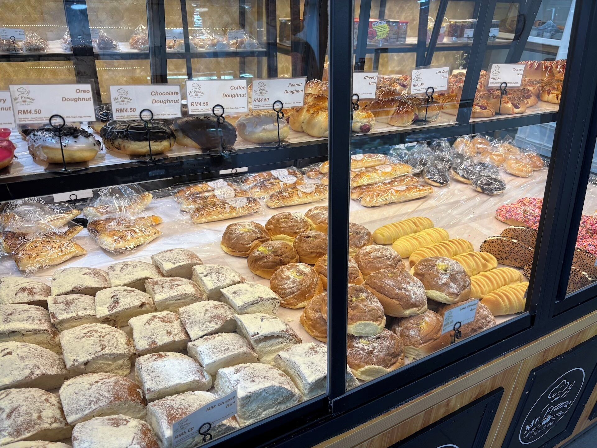 A bakery display case with various baked goods like doughnuts, buns, and pastries.