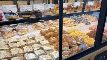 A bakery display case with various baked goods like doughnuts, buns, and pastries.