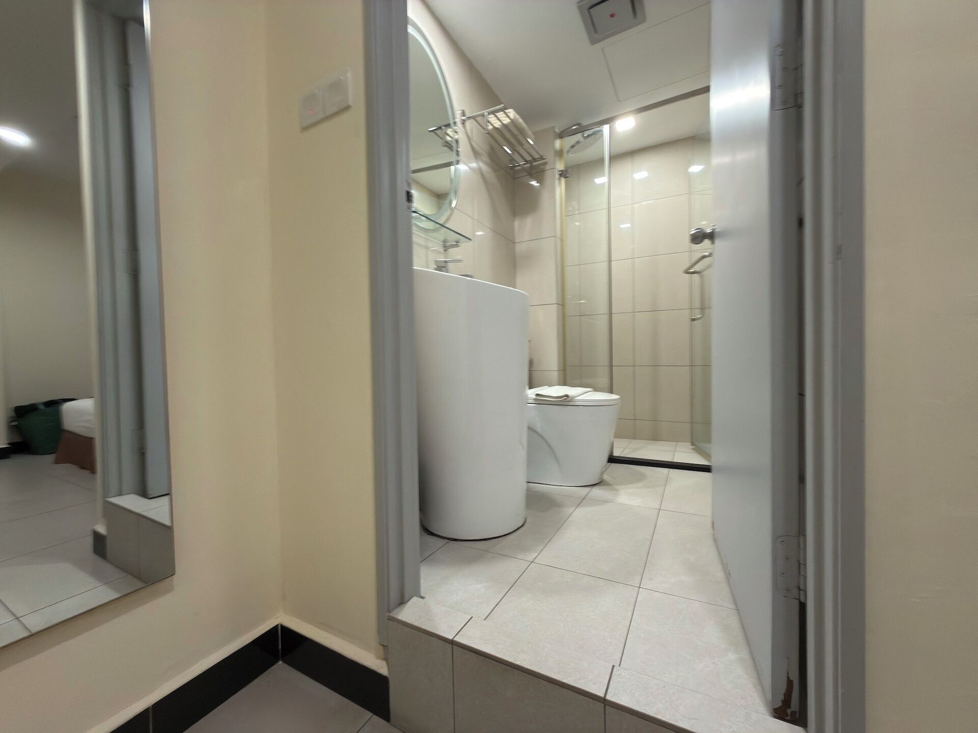 A bathroom with a toilet, a shower, and a mirror.
