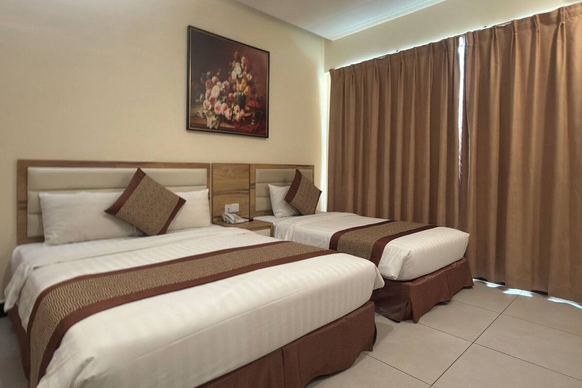 Habitación de hotel con dos camas, un cuadro en la pared y un ventanal con cortinas.