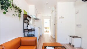 Ein modernes Wohnzimmer mit einer Couch, einem Couchtisch und einer Küche im Hintergrund.