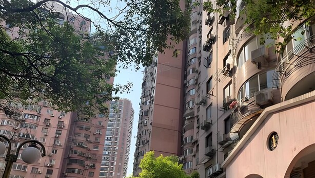 Un quartier résidentiel composé d’immeubles à étages, d’un chemin bordé d’arbres et d’un bâtiment doté d’une entrée en arc de cercle.