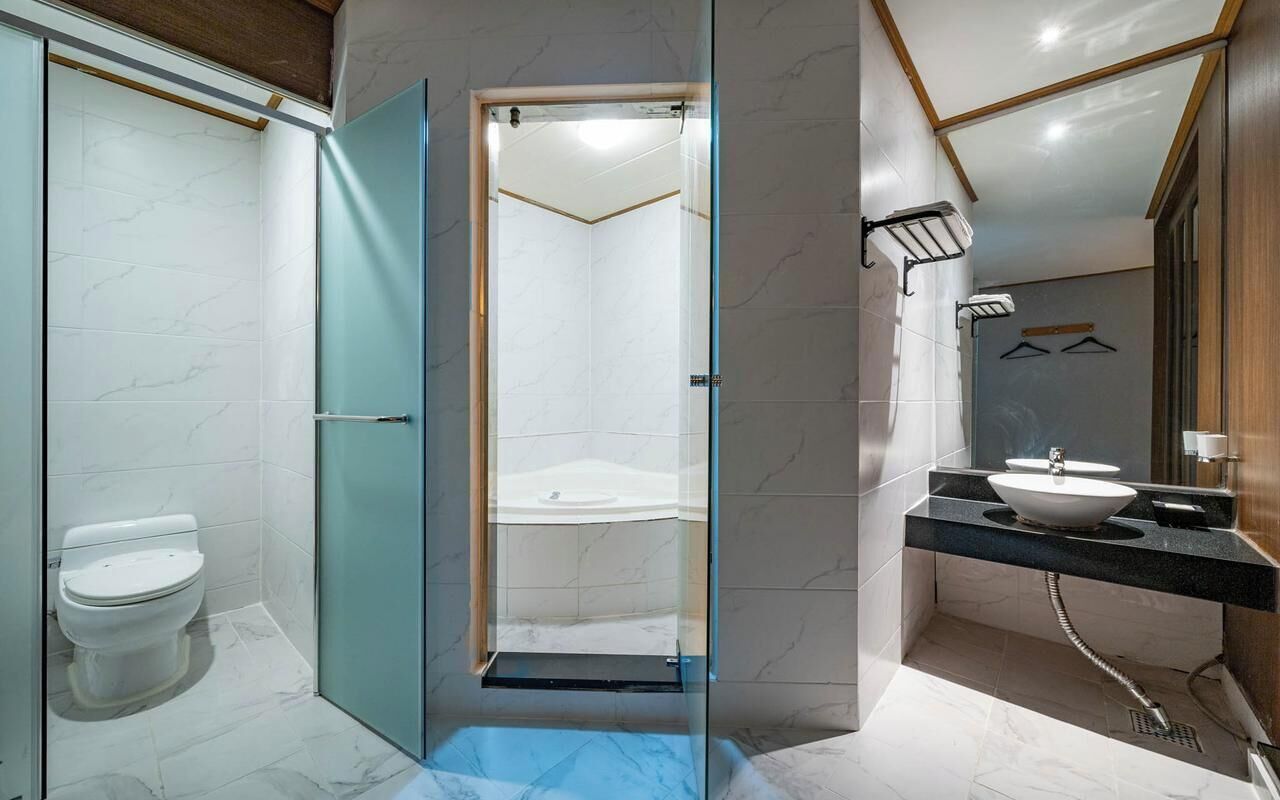 A modern bathroom with a glass-enclosed shower, a toilet, and a sink with a mirror.
