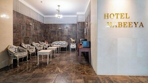 A hotel lobby with a seating area, a reception desk, and a wall-mounted sign reading 'HOTEL NABEYA'. - Hasen Nabeeya Hotel (Siheung)