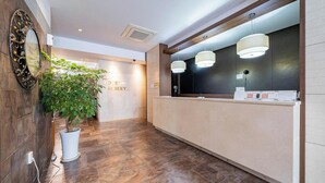 A hotel reception area with a wooden floor, a reception desk, and a potted plant. - Hasen Nabeeya Hotel (Siheung)
