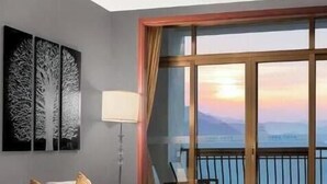 A room with a bed, a window with a view of the sunset, and a painting on the wall. - Avatar Valley Grand Hotel (Zhangjiajie)