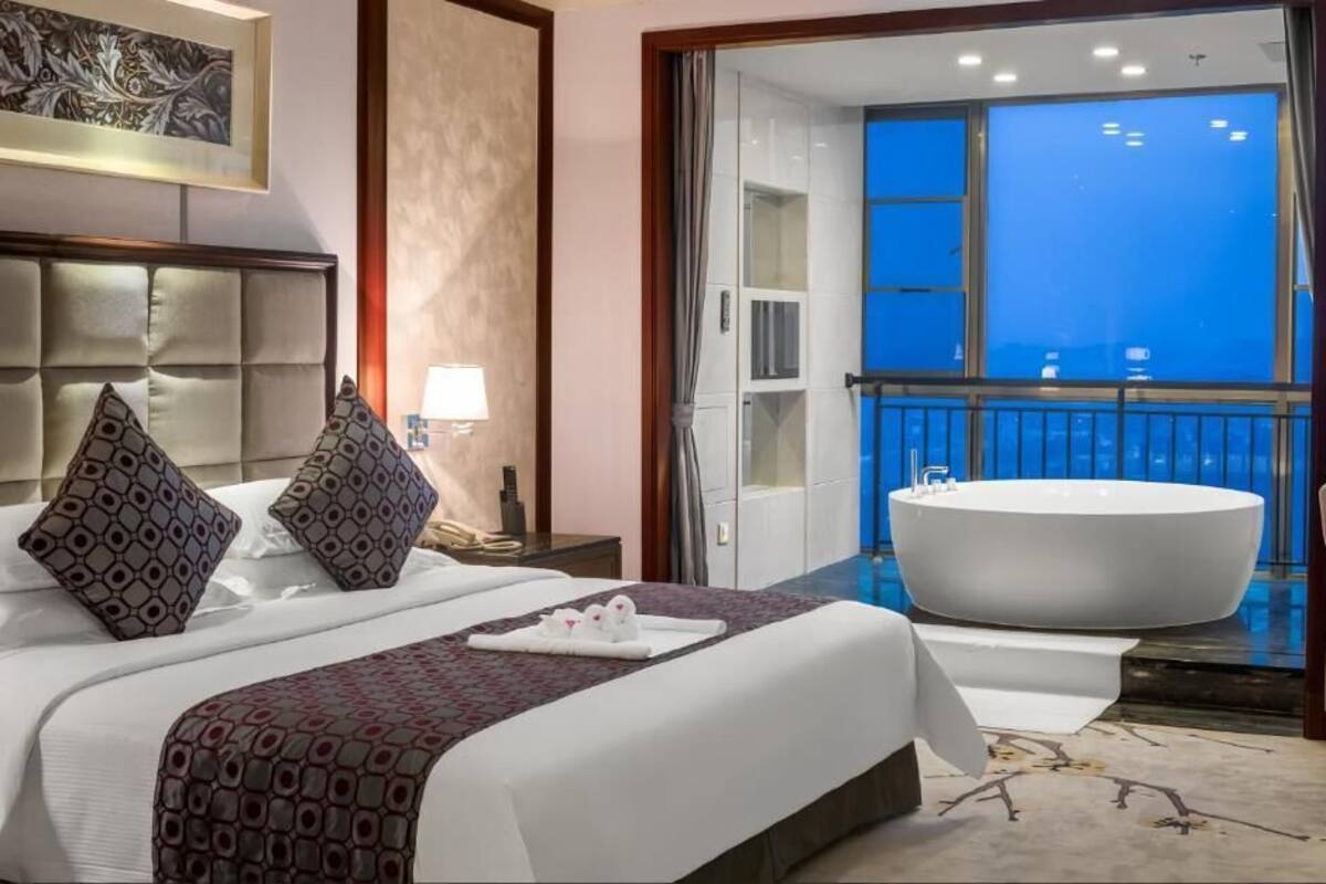 Une chambre d’hôtel avec un grand lit, une baignoire et un balcon avec vue.