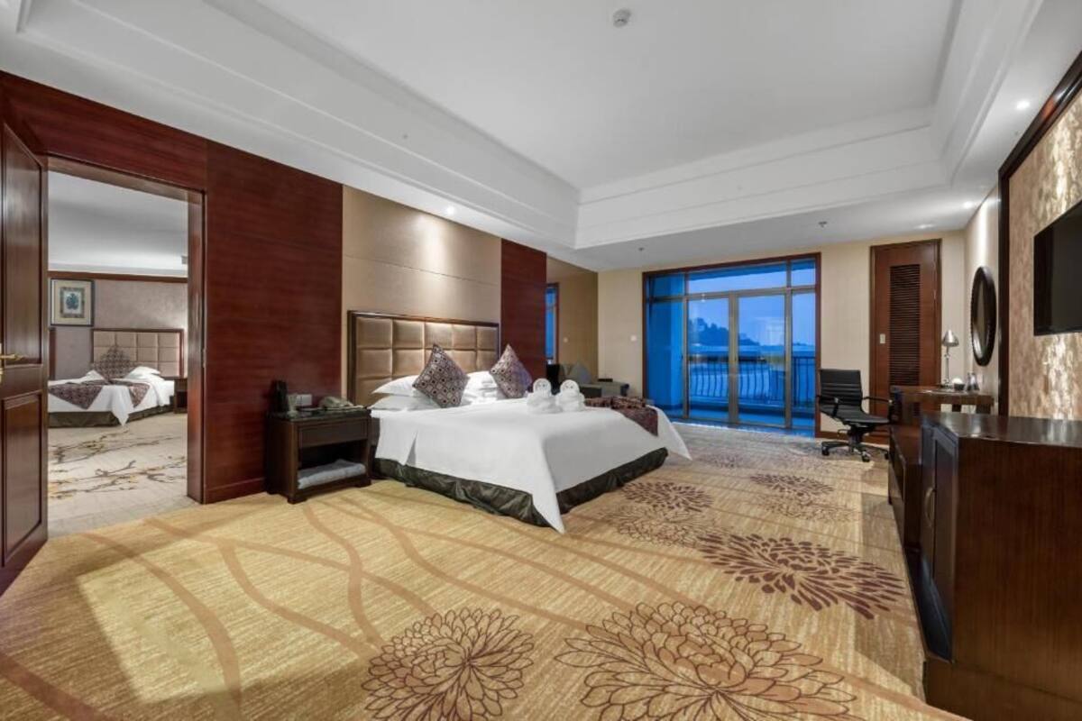 Une chambre d’hôtel avec un grand lit, un bureau, une télévision et une vue sur l’extérieur.