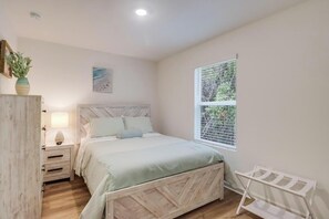A bedroom with a bed, bedside table, lamp, window, and a plant. - Cozy Gulfport Beach Home - Seahorse Harbor (Gulfport)
