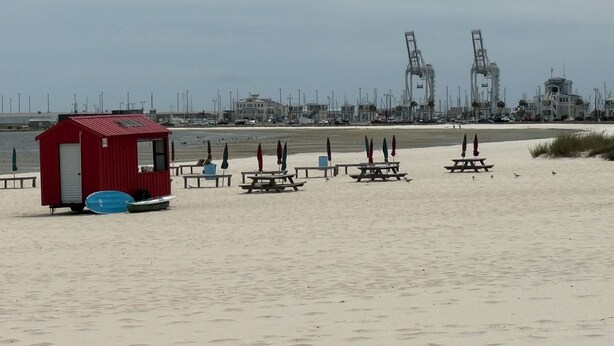 A beach with a lifeguard station, picnic tables, and beach umbrellas. - Cozy Gulfport Beach Home - Seahorse Harbor (Gulfport)