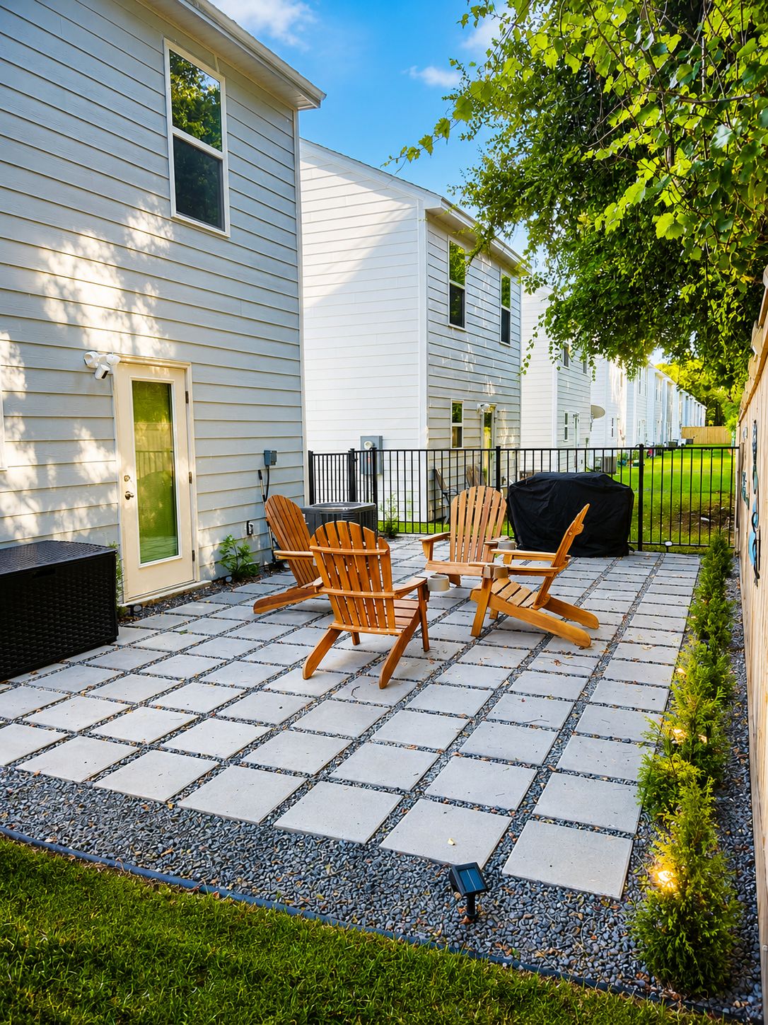 Eine Terrasse mit Adirondack-Stühlen, einem Grill und einer kleinen solarbetriebenen Beleuchtung.