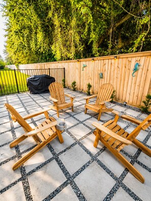 A patio with wooden chairs and a table, surrounded by a wooden fence with decorative elements. - Cozy Gulfport Beach Home - Seahorse Harbor (Gulfport)