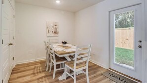 A dining area with a table and chairs, a door with a window, and a small outdoor area visible through the door. - Cozy Gulfport Beach Home - Seahorse Harbor (Gulfport)