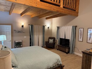 A bedroom with a bed, a chair, a TV, and a wooden ceiling. - Serene 4-bedroom  spacious house in Pagosa Springs perfect for your getaway. (Pagosa Springs)