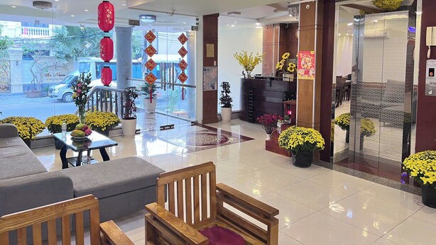 Una hall d'albergo con posti a sedere, una reception e piante ornamentali.