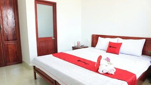 Una camera d'albergo con un letto in legno, un comodino, uno specchio e un armadio.