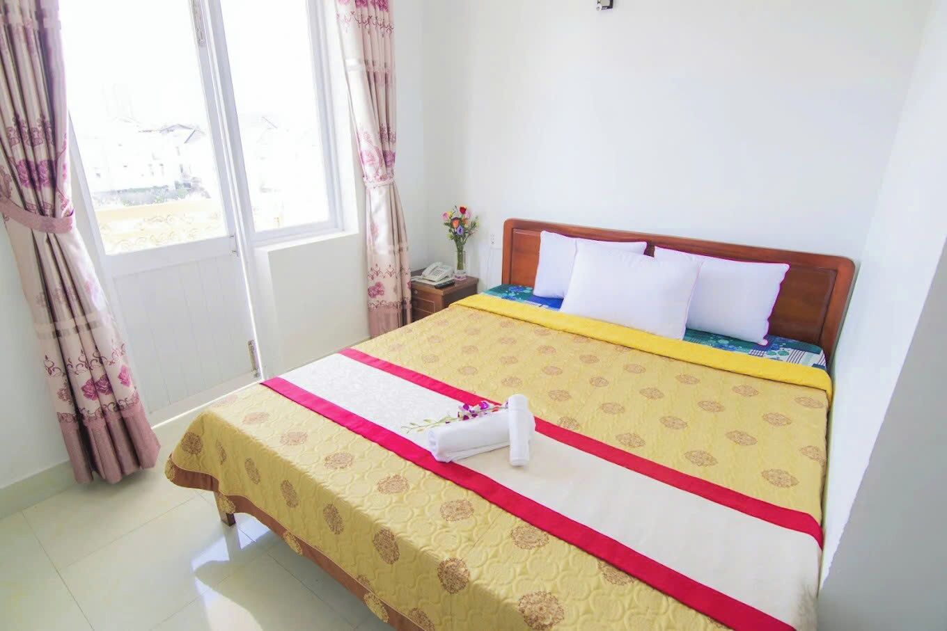 Une chambre d’hôtel avec un lit, une table de chevet, une fenêtre avec des rideaux et une vue sur l’extérieur.