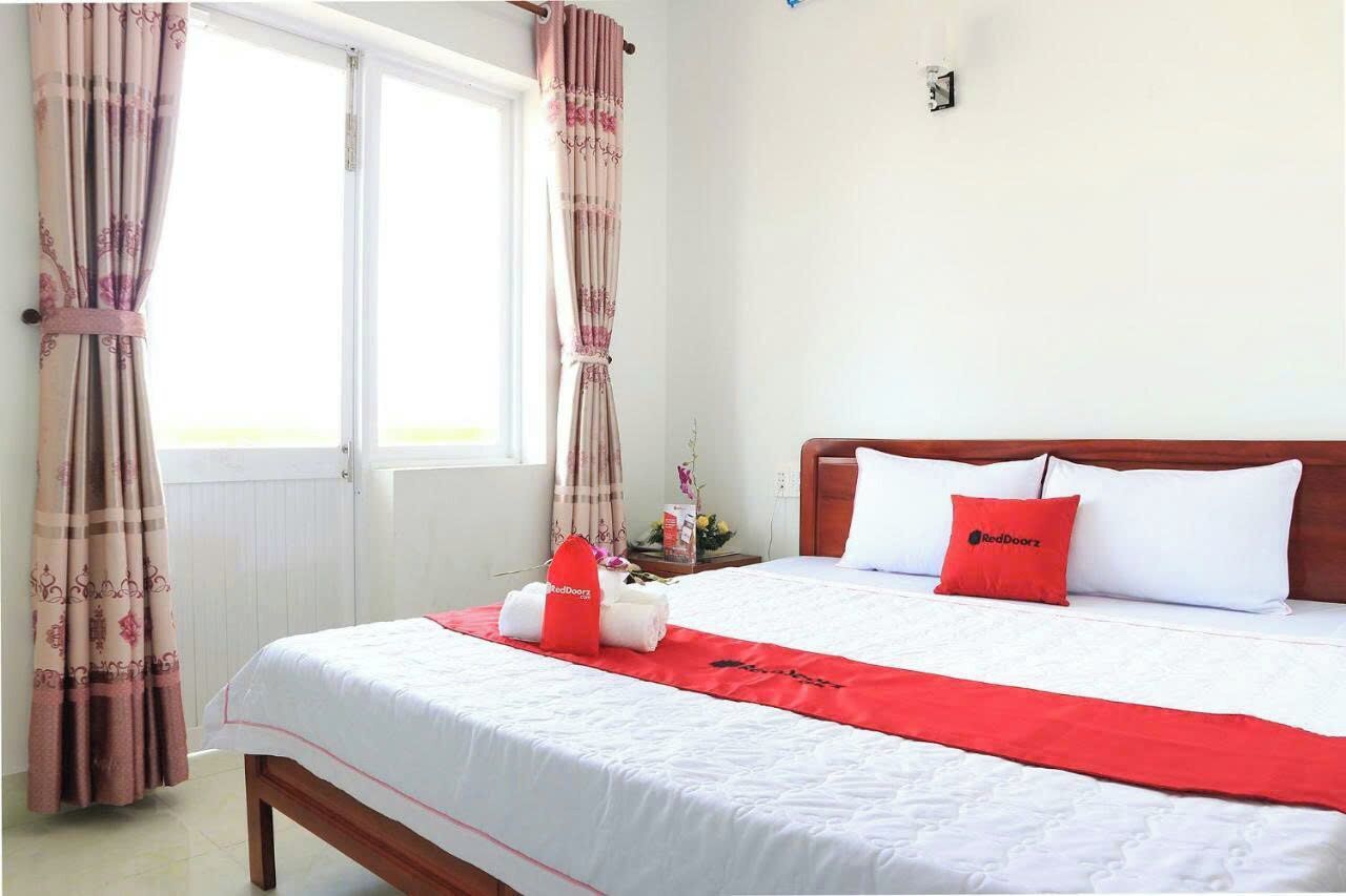 A hotel room with a bed, curtains, a nightstand, and a window.