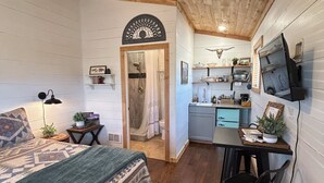 A cozy room with a bed, a small table, a chair, a kitchenette, and a ceiling fan. - Relaxing Rustic Barndominium with Mountain View’s in Challis Idaho (Challis)