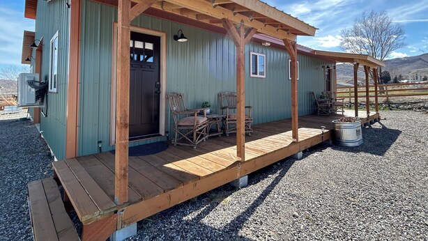 A rustic cabin with a wooden deck, a porch, and a door. - Relaxing Rustic Barndominium with Mountain View’s in Challis Idaho (Challis)
