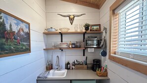 A compact kitchen with a sink, a microwave, and a window with blinds. - Relaxing Rustic Barndominium with Mountain View’s in Challis Idaho (Challis)