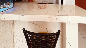 A kitchen with a marble countertop, hanging pendant lights, a black woven chair, a fish tank, and a refrigerator. - Bossa Nova Home - a private house 5 minutes from the beach with Brazilian style! (Barra dos Coqueiros)