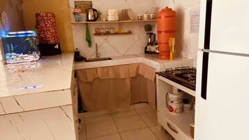 Uma cozinha compacta com geladeira branca, pia, fogão e um aquário.