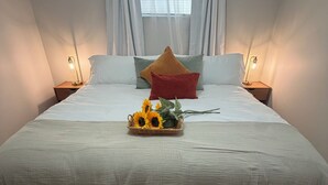 A neatly made bed with a white bedspread, two pillows, and a decorative basket with sunflowers. - Garden Estate at the base of the Mountains, sleeps 16, near BYU (Orem)