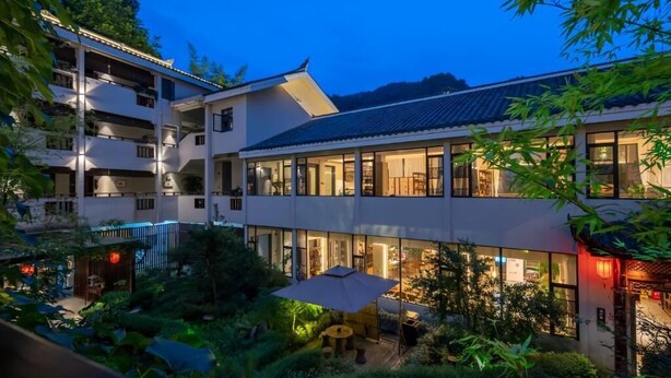 A multi-story building with a courtyard, large windows, and a traditional-style entrance. - Serene Peaks Courtyard (Xiangxi)