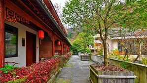A traditional courtyard with wooden buildings, a stone pathway, and a tree. - Serene Peaks Courtyard (Xiangxi)