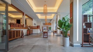 A spacious lobby with a high ceiling, a central staircase, and a large potted plant. - Serene Peaks Courtyard (Xiangxi)