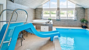 A swimming pool with a slide, a hot tub, and a window with a view of the outside. - 5 Star Holiday Home in Norre Nebel (Norre Nebel)